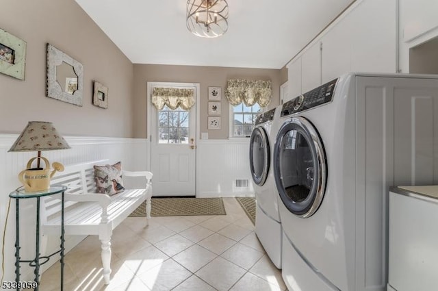 laundry area with light tile patterned floors, a chandelier, a wainscoted wall, laundry area, and washer and clothes dryer