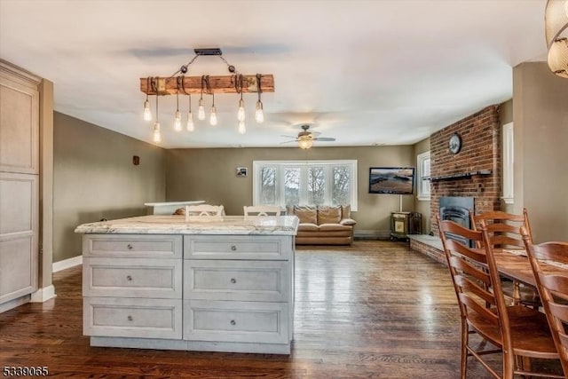 interior space with decorative light fixtures, dark wood-type flooring, light stone counters, and a center island