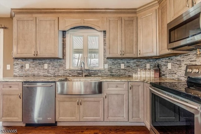 kitchen with stainless steel appliances, light brown cabinetry, light stone countertops, and sink