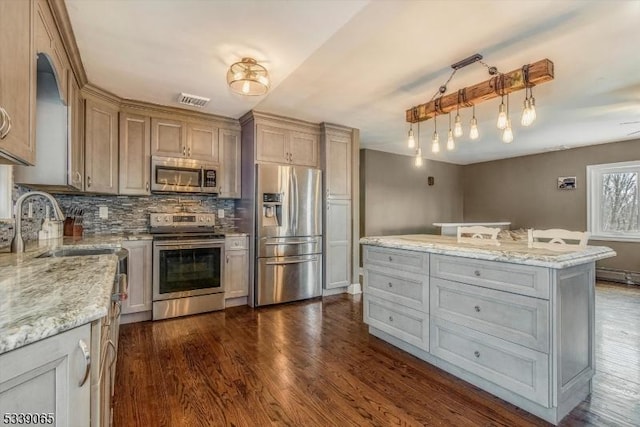 kitchen featuring appliances with stainless steel finishes, a kitchen island, dark hardwood / wood-style flooring, and light stone counters