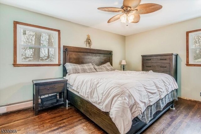 bedroom with ceiling fan, dark wood-type flooring, and a baseboard heating unit