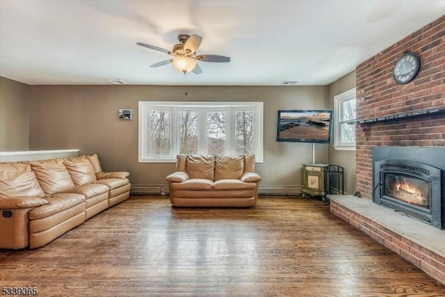 living room featuring a brick fireplace, hardwood / wood-style floors, and ceiling fan