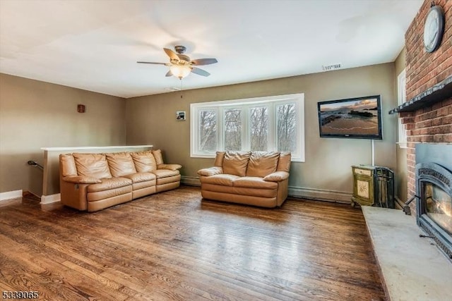 living room with ceiling fan, dark hardwood / wood-style floors, a brick fireplace, and a baseboard radiator