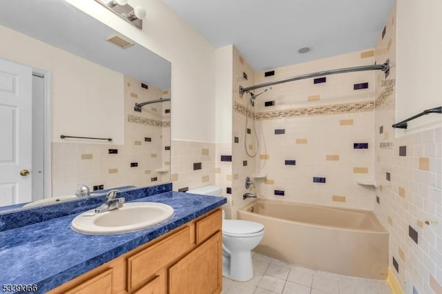 full bathroom featuring tiled shower / bath combo, toilet, tile walls, tile patterned floors, and vanity