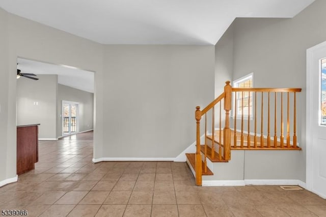 staircase with lofted ceiling, tile patterned flooring, and ceiling fan