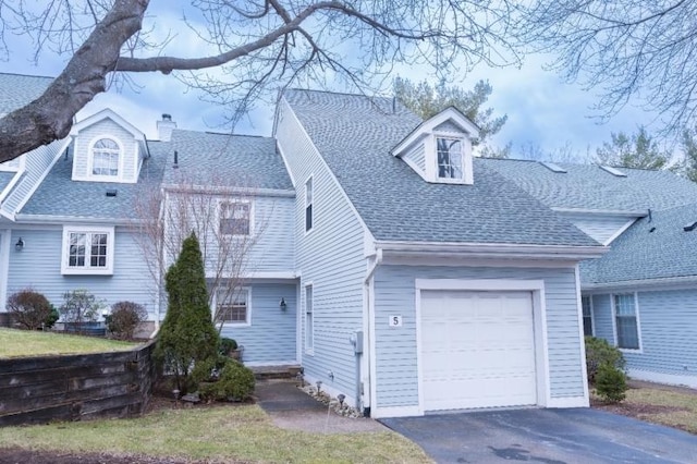 view of front of house with an attached garage, driveway, a chimney, and roof with shingles