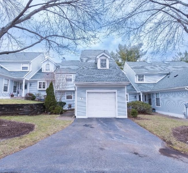 view of front facade featuring aphalt driveway, a front lawn, a shingled roof, and an attached garage