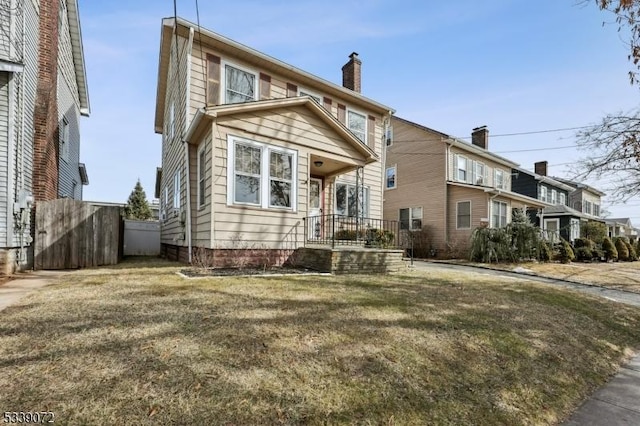 view of front of house with fence, a chimney, and a front lawn