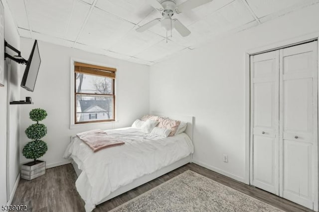 bedroom featuring dark wood-style floors, ceiling fan, a closet, and baseboards