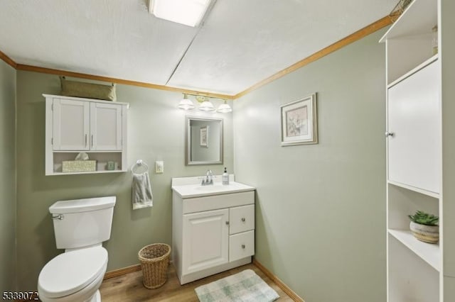 bathroom with baseboards, vanity, toilet, and wood finished floors