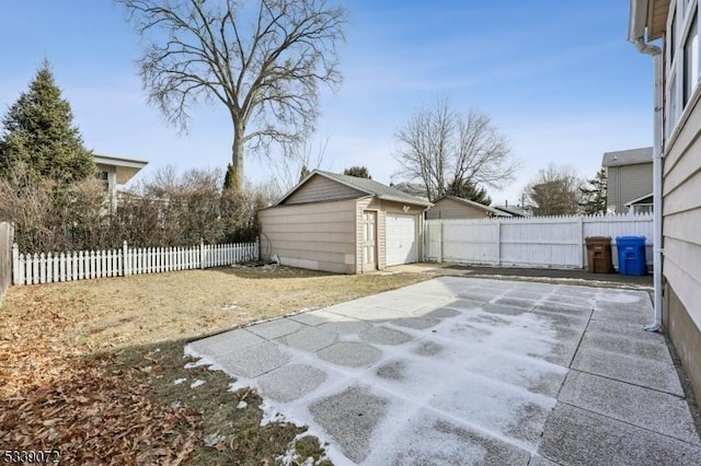 view of patio featuring a fenced backyard, a detached garage, and an outbuilding