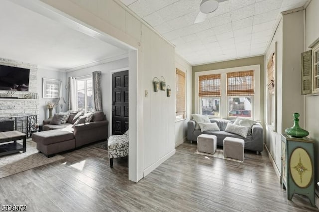 living area featuring crown molding, a fireplace, baseboards, and wood finished floors