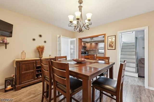 dining space with light wood-style flooring, baseboards, and stairs