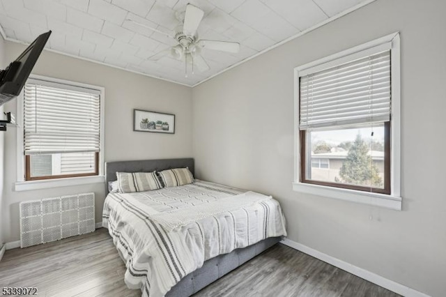 bedroom with wood finished floors, visible vents, and baseboards