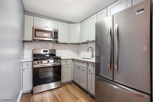 kitchen featuring light hardwood / wood-style flooring, stainless steel appliances, tasteful backsplash, and sink