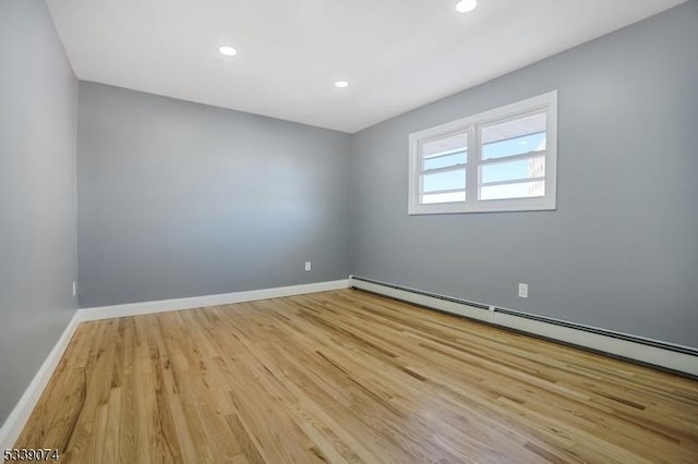 empty room featuring light wood-type flooring and a baseboard heating unit