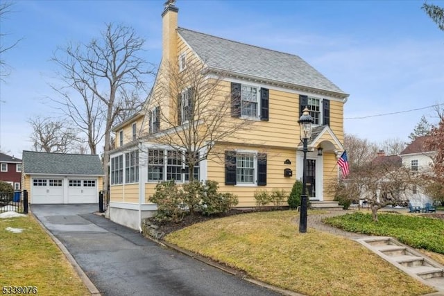 view of front of home with an outdoor structure, a chimney, and a front lawn