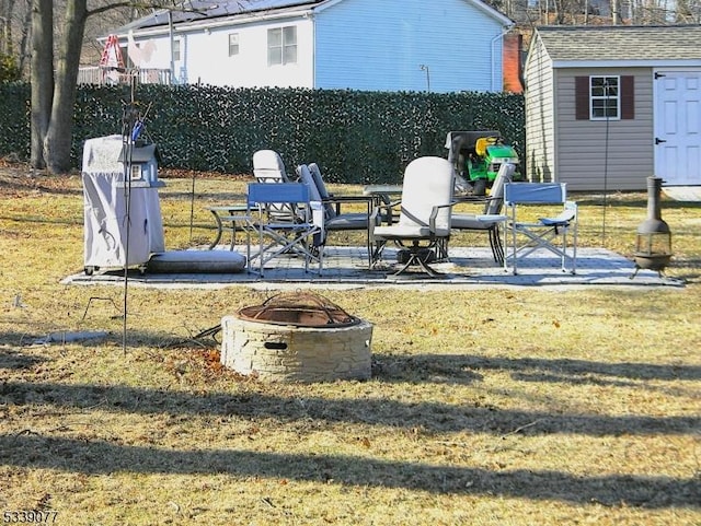 exterior space with a fire pit, fence, a shed, a patio area, and an outbuilding