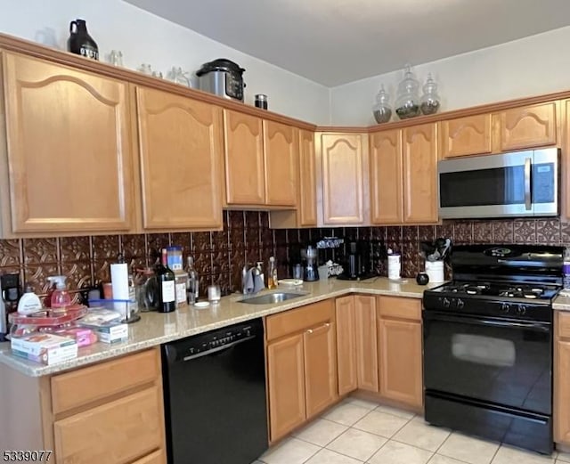 kitchen with backsplash, light tile patterned flooring, a sink, light stone countertops, and black appliances