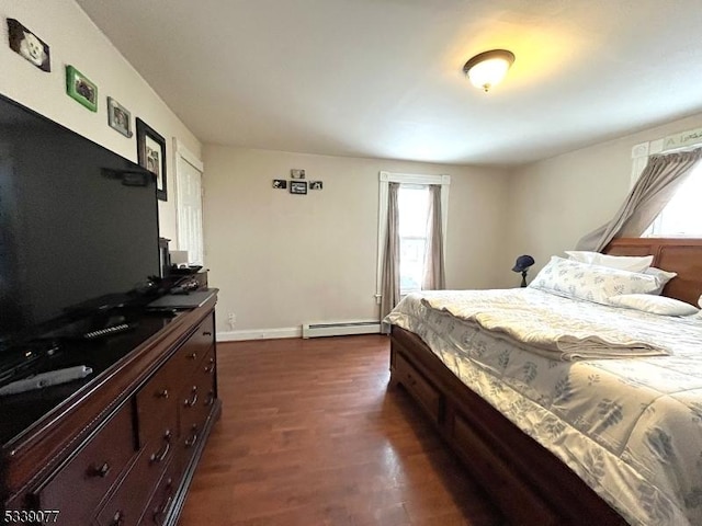 bedroom with a baseboard heating unit, baseboards, and dark wood finished floors