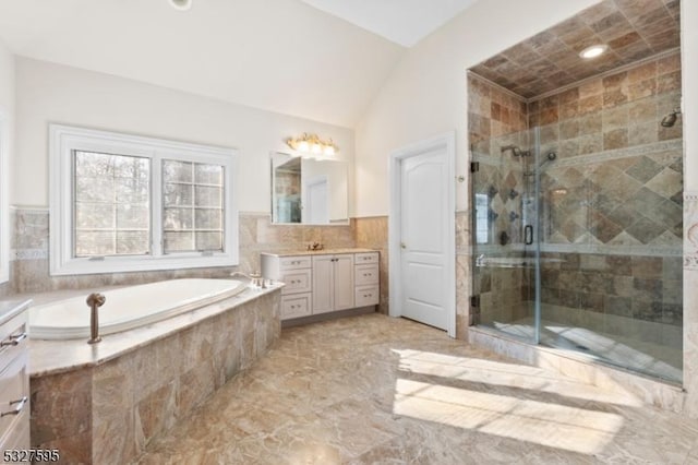 bathroom featuring separate shower and tub, vanity, and vaulted ceiling