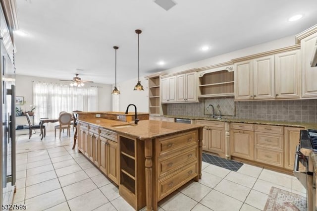 kitchen with an island with sink, light tile patterned flooring, pendant lighting, sink, and stainless steel range