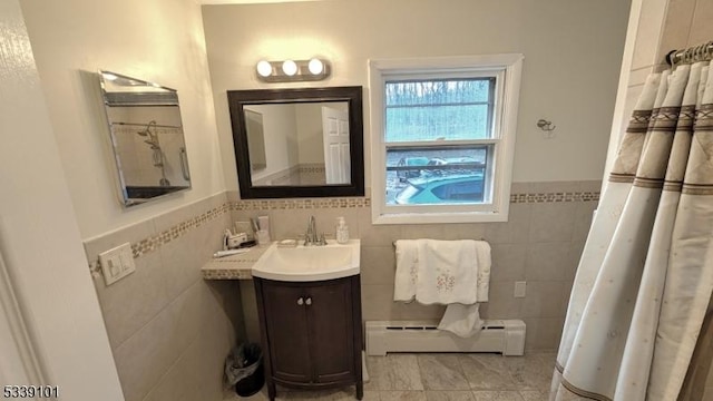 bathroom with a baseboard radiator, tile walls, and vanity