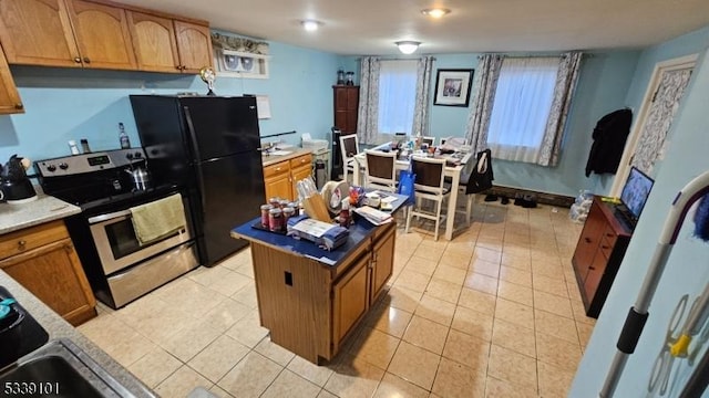 kitchen with electric range, black refrigerator, a center island, and light tile patterned floors