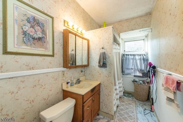 bathroom with wainscoting, vanity, toilet, and wallpapered walls