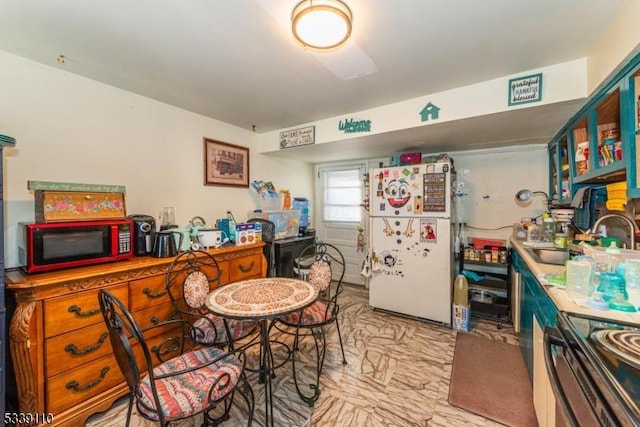 kitchen featuring marble finish floor, black range with electric stovetop, a sink, and freestanding refrigerator