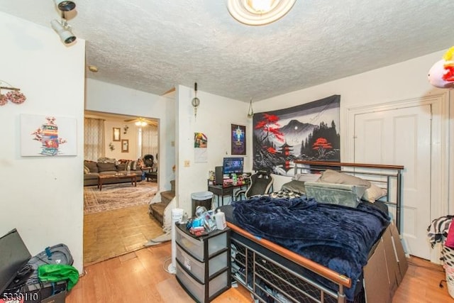 bedroom with a textured ceiling and wood finished floors