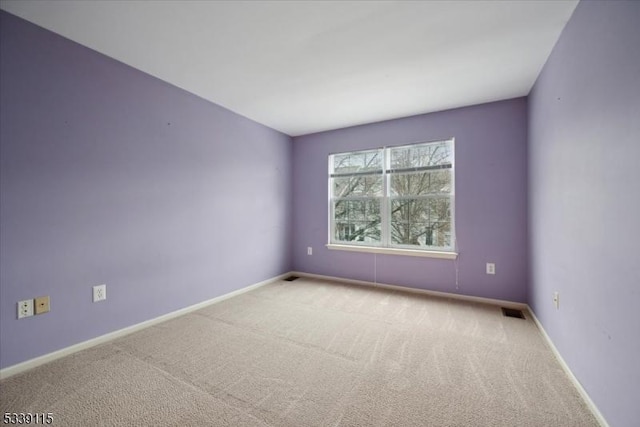 spare room with baseboards, visible vents, and light colored carpet