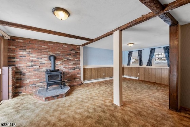 unfurnished living room with carpet, a wood stove, beamed ceiling, and wood walls