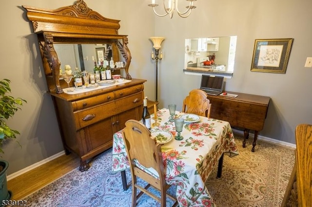 dining space featuring a notable chandelier, wood finished floors, and baseboards