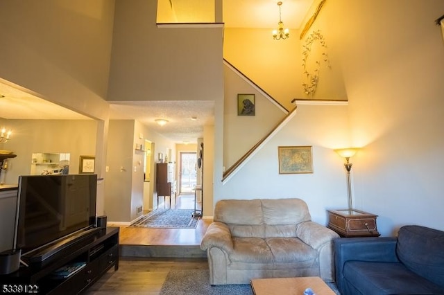 living room with an inviting chandelier, a high ceiling, stairway, and wood finished floors