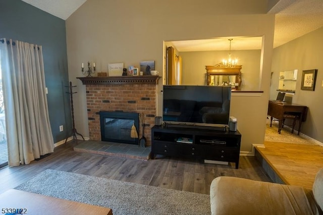 living room featuring lofted ceiling, a brick fireplace, a chandelier, and wood finished floors