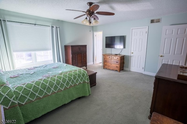 carpeted bedroom featuring a textured ceiling, baseboards, visible vents, and a ceiling fan