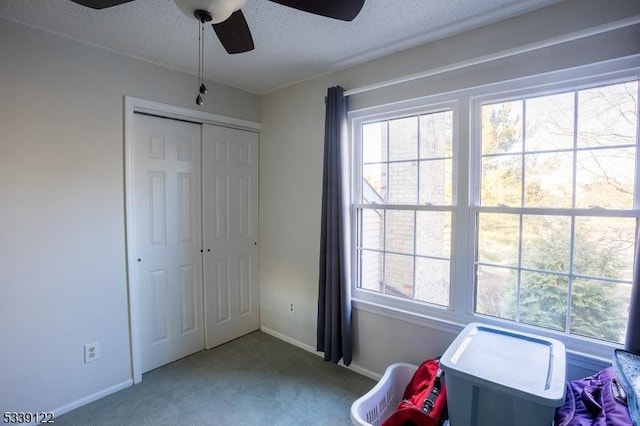 unfurnished bedroom with a textured ceiling, ceiling fan, carpet floors, baseboards, and a closet