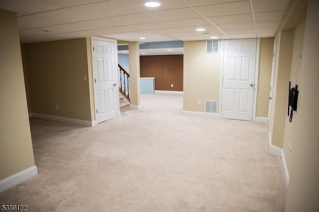 finished below grade area with baseboards, stairs, visible vents, and light colored carpet