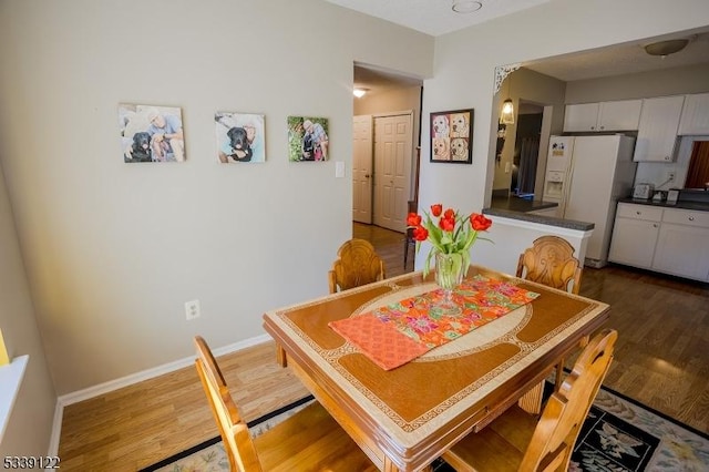 dining space featuring baseboards and dark wood-style flooring