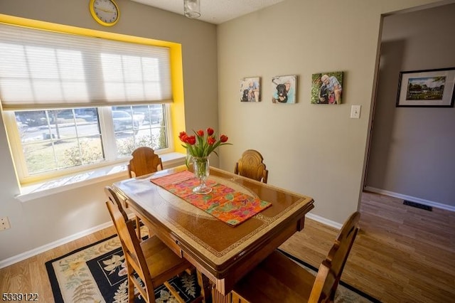 dining space with visible vents, baseboards, and wood finished floors