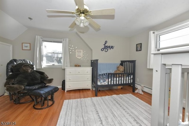 bedroom featuring ceiling fan, light hardwood / wood-style flooring, baseboard heating, and lofted ceiling