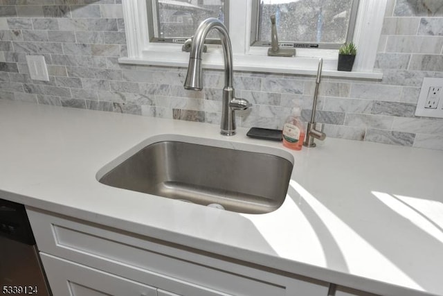 interior details with sink, stainless steel dishwasher, and decorative backsplash