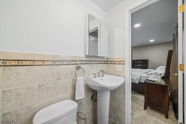 bathroom featuring sink, toilet, and tile walls