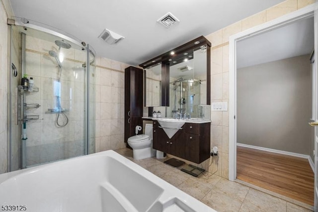 full bathroom featuring independent shower and bath, tile walls, vanity, tile patterned flooring, and toilet