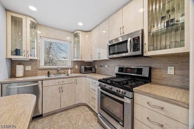 kitchen featuring sink, stainless steel appliances, decorative backsplash, and light tile patterned floors