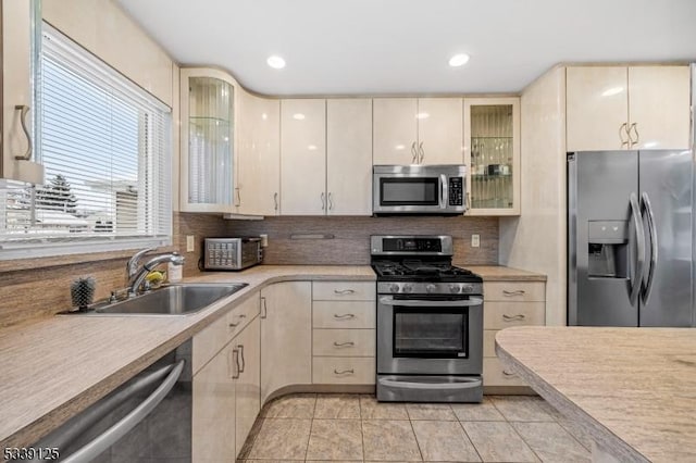 kitchen with sink, stainless steel appliances, decorative backsplash, and light tile patterned floors