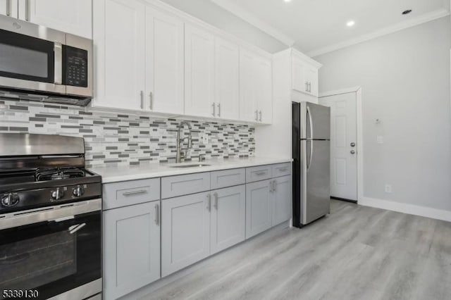 kitchen featuring appliances with stainless steel finishes, ornamental molding, a sink, light countertops, and backsplash