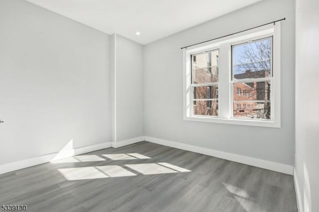 spare room featuring recessed lighting, wood finished floors, and baseboards