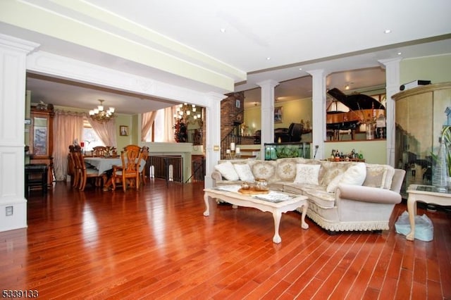 living room with a chandelier, wood finished floors, decorative columns, and stairs